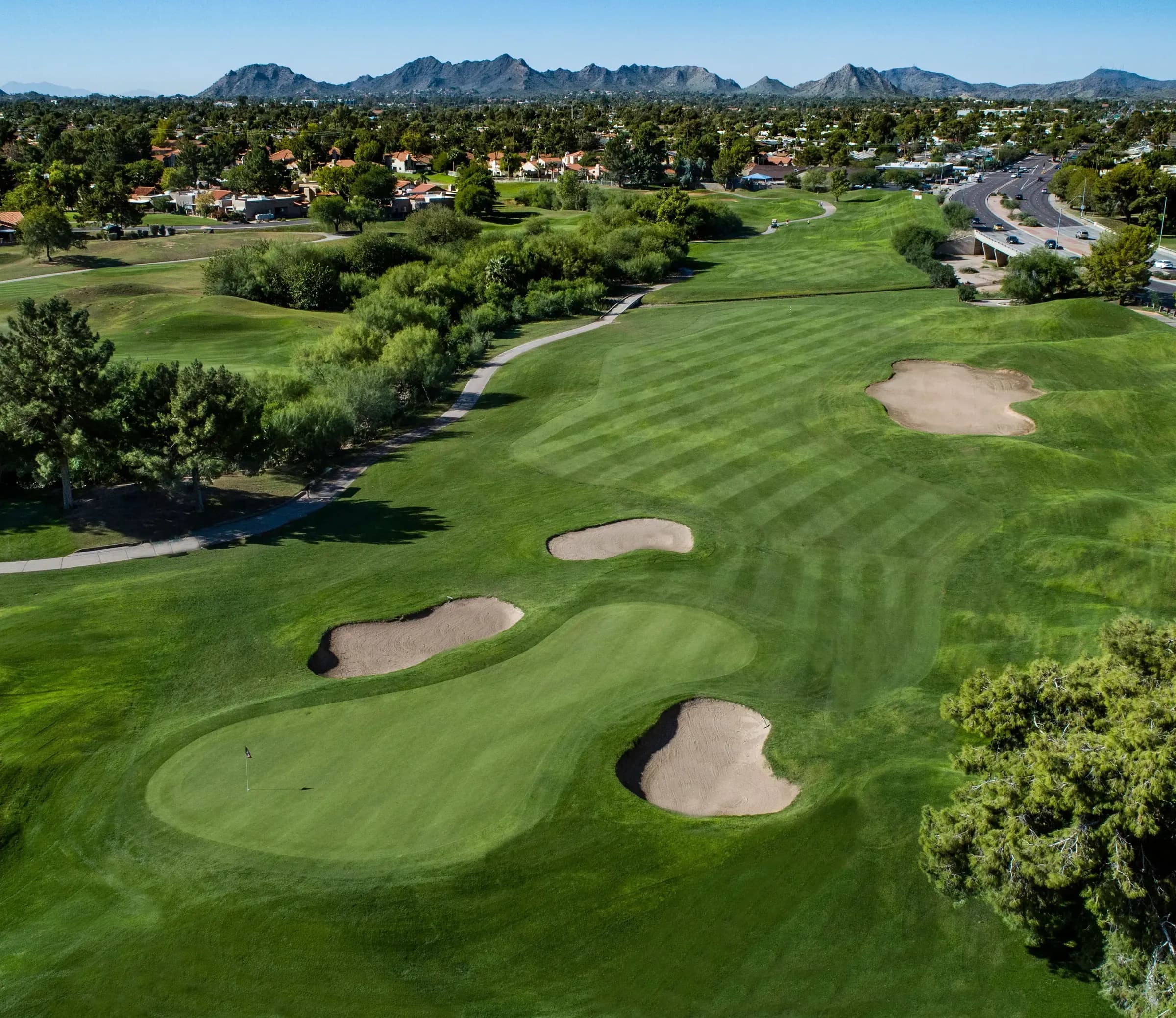 Aerial view of the eighth green ringed by bunkers, with the mountains on the horizon
